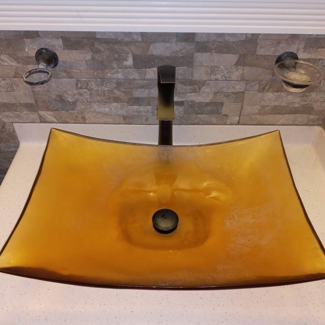 Amber glass vessel sink with black tap